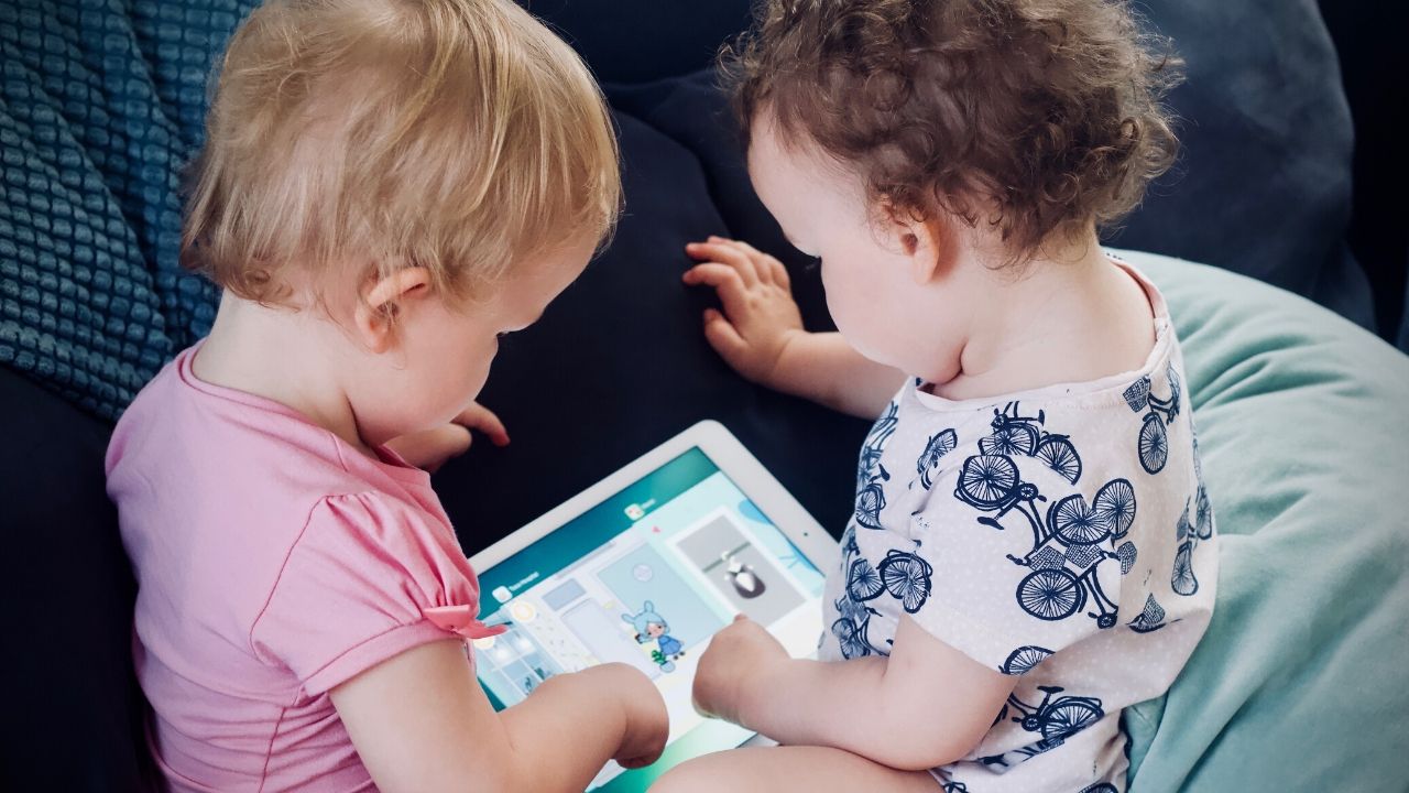 featured photo of two toddlers looking at a tablet, possibly listening to audio books for kids