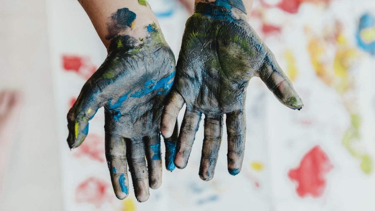 photo of a child's hands covered in paint, which is just one of the essential craft supplies for toddlers