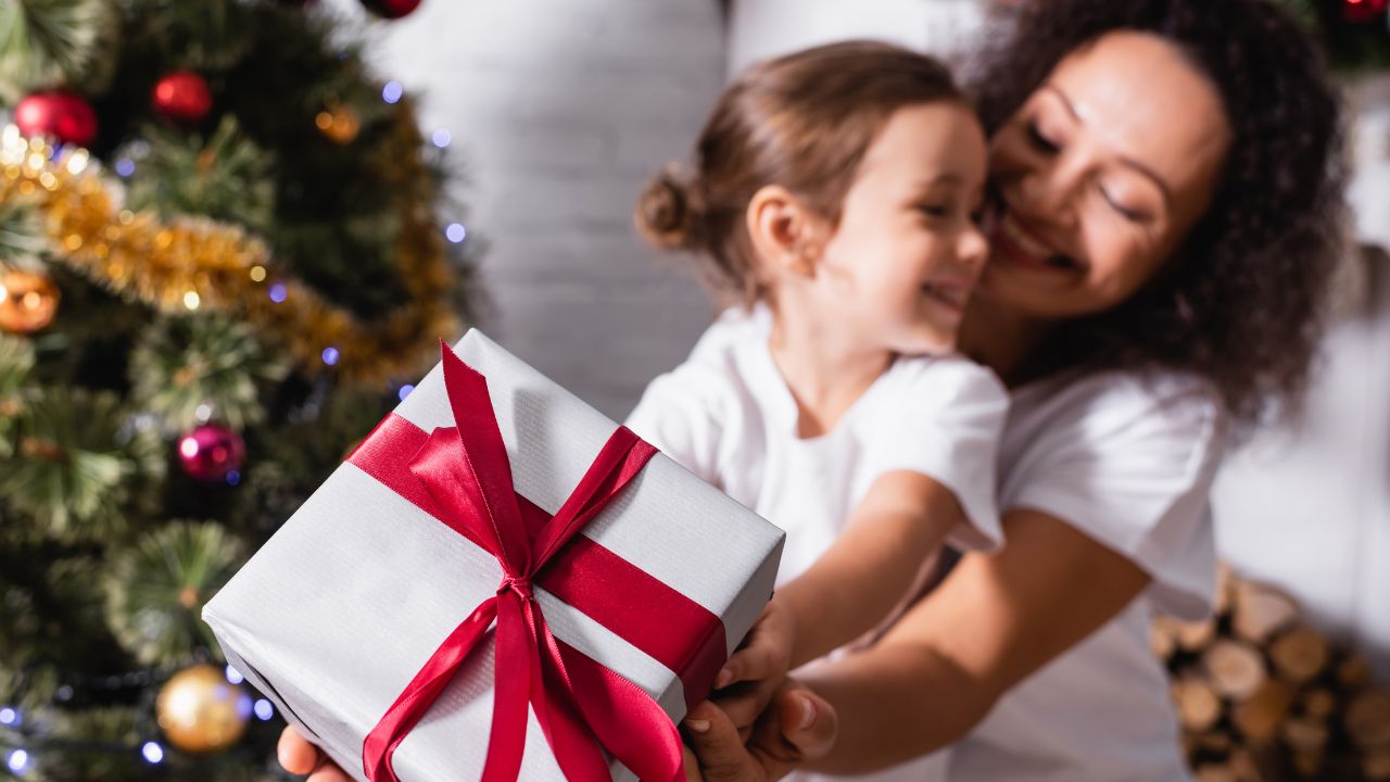 mom and preschool age daughter holding a christmas gift