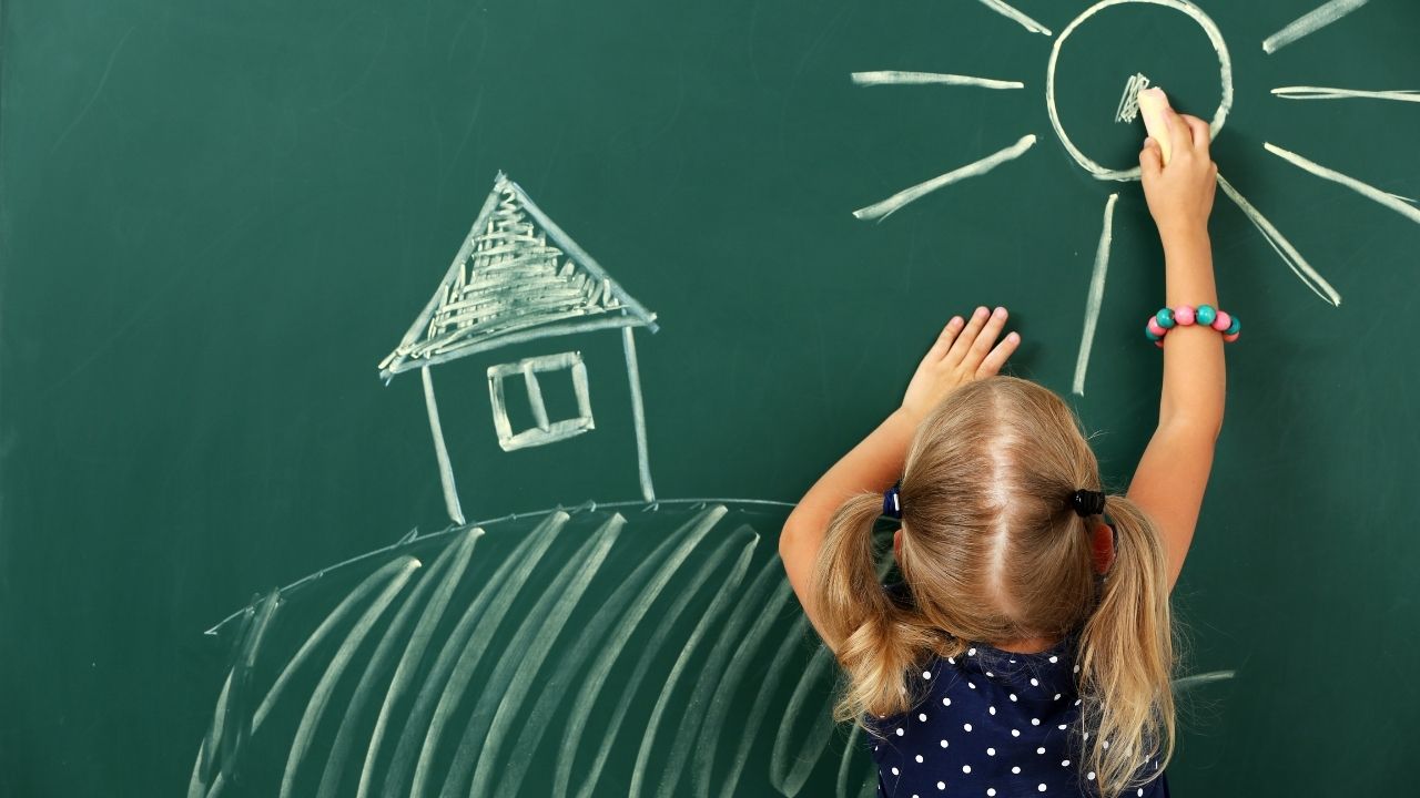 young child drawing on a chalkboard - featured image for article on what to pack for preschool