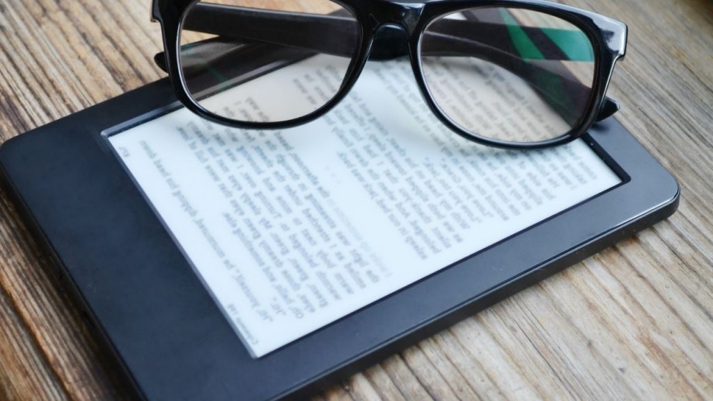photo of an e-reader with reading glasses resting on top of it