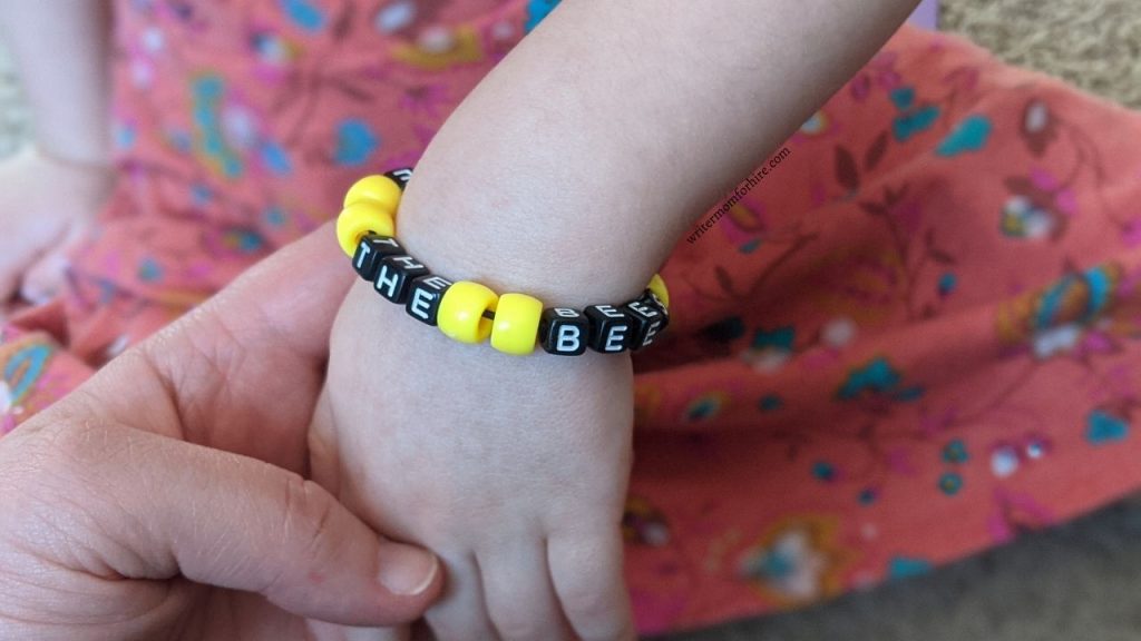 child wearing a save the bees bracelet made with supplies from the green kid crafts box