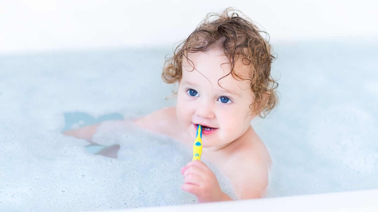 toddler brushing teeth in the bathtub