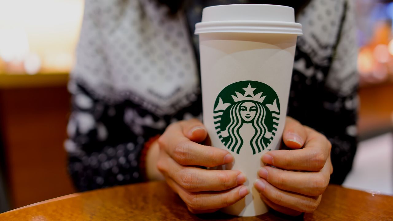 woman holding a starbucks drink cup in her hands