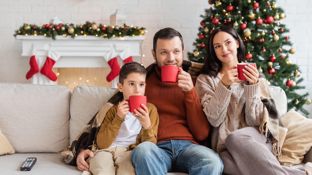 family drinking hot cocoa while watching a movie on their christmas movies bucket list
