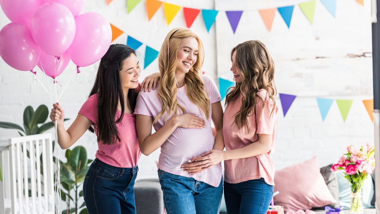 women talking and laughing with baby shower decorations in the background