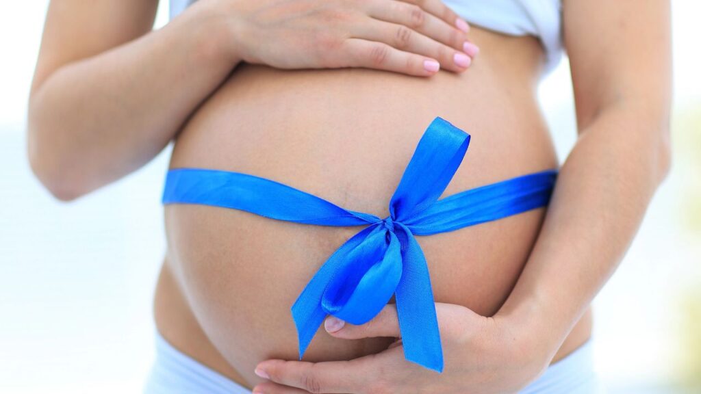 pregnant belly with a blue ribbon wrapped around it