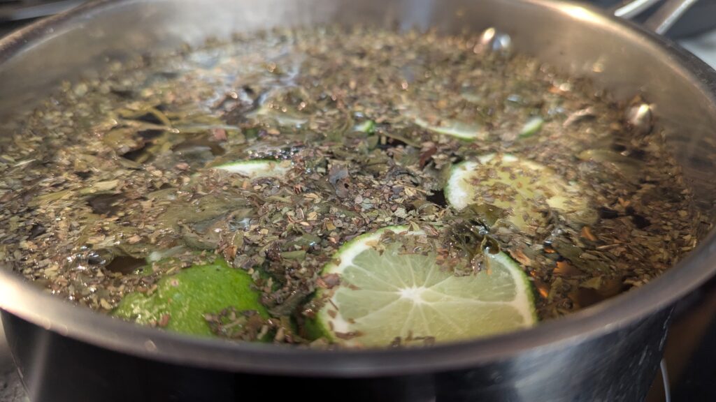 mint green tea leaves and sliced lime in a simmering pot of water